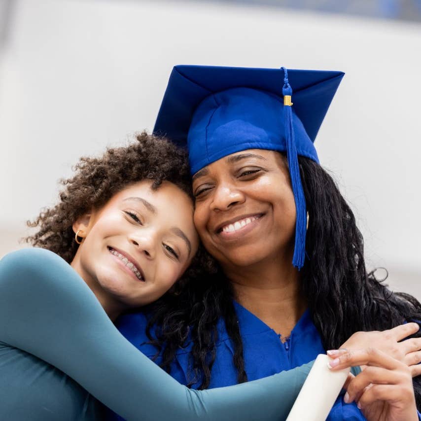 Adult graduate poses for photo with her preteen daughter on graduation day